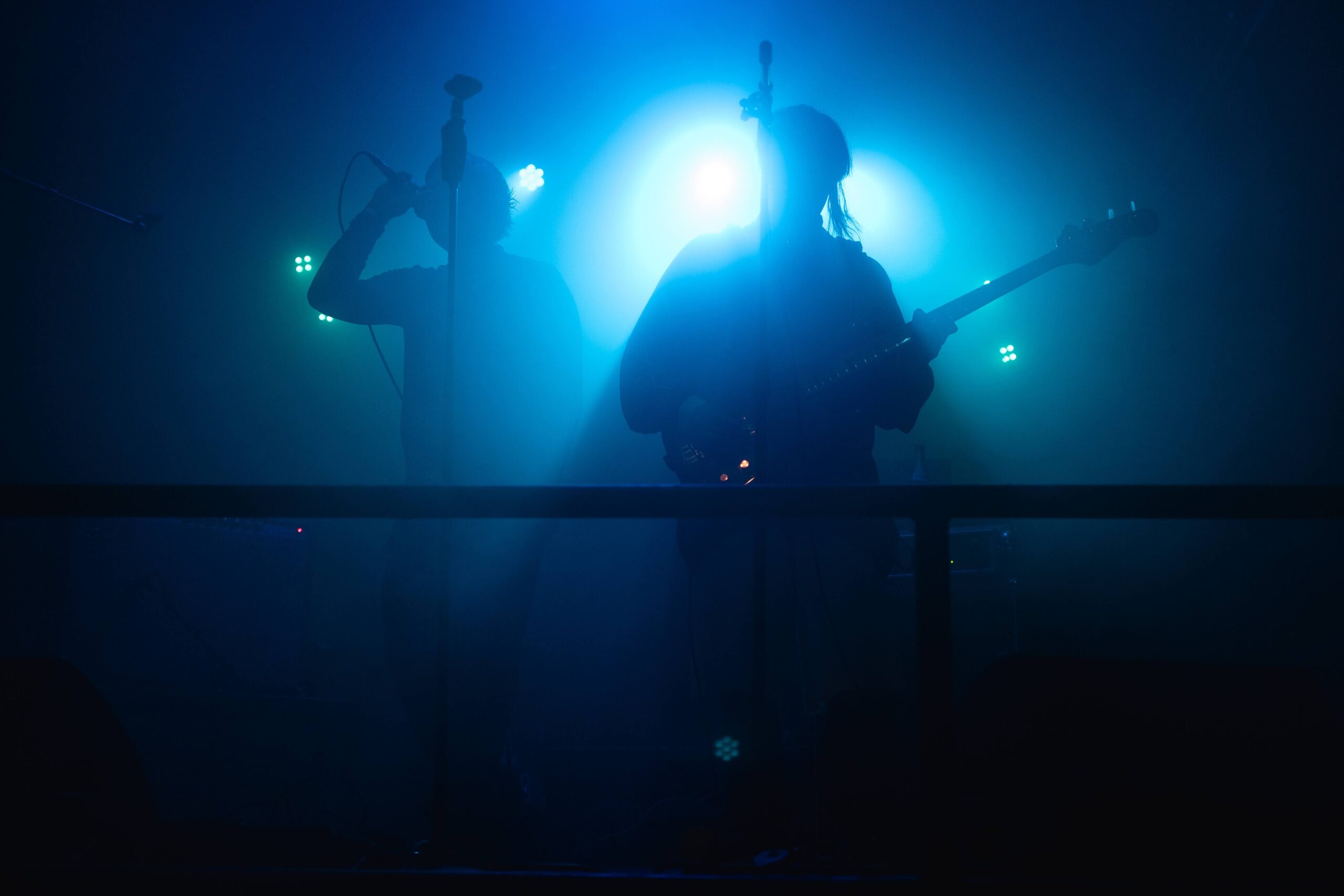 ENNS stehen in grellem Bühnenlicht mit Gitarre und Mikrofon
